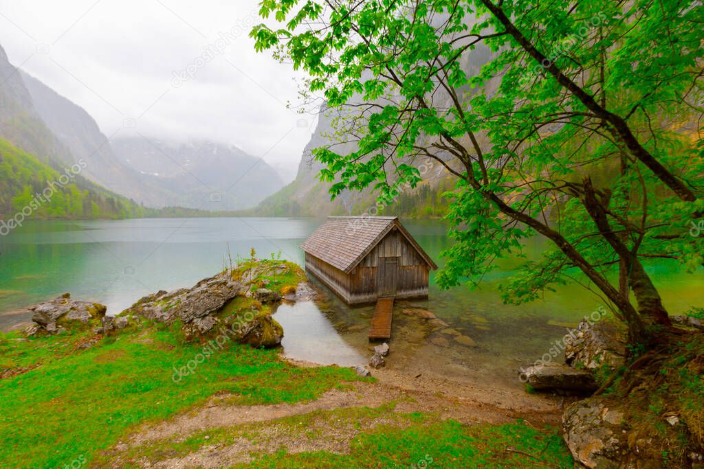 Idyllic view of traditional old wooden boat house at scenic Lake Obersee on a beautiful sunny day with blue sky and clouds in summer, Nationalpark Berchtesgadener Land, Bavaria, Germany