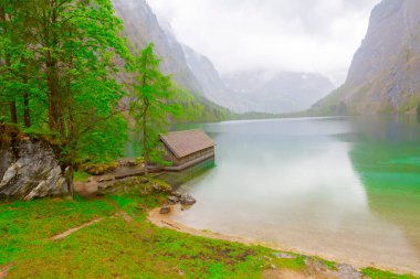 Yaz aylarında mavi gökyüzü ve bulutlar ile güzel bir güneşli bir günde doğal Obersee Gölü'nde geleneksel eski ahşap tekne evi Pastoral görünümü, Millipark Berchtesgadener Land, Bavyera, Almanya
