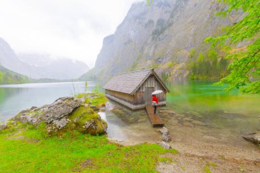 Yaz aylarında mavi gökyüzü ve bulutlar ile güzel bir güneşli bir günde doğal Obersee Gölü'nde geleneksel eski ahşap tekne evi Pastoral görünümü, Millipark Berchtesgadener Land, Bavyera, Almanya