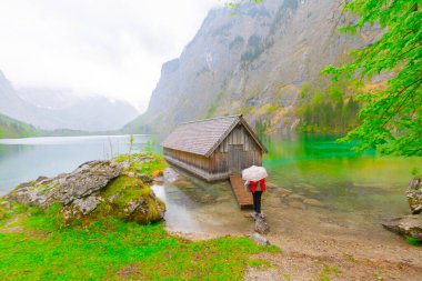 Yaz aylarında mavi gökyüzü ve bulutlar ile güzel bir güneşli bir günde doğal Obersee Gölü'nde geleneksel eski ahşap tekne evi Pastoral görünümü, Millipark Berchtesgadener Land, Bavyera, Almanya