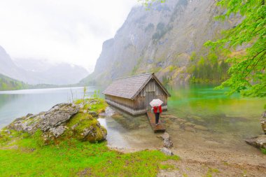 Yaz aylarında mavi gökyüzü ve bulutlar ile güzel bir güneşli bir günde doğal Obersee Gölü'nde geleneksel eski ahşap tekne evi Pastoral görünümü, Millipark Berchtesgadener Land, Bavyera, Almanya