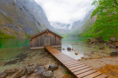 Yaz aylarında mavi gökyüzü ve bulutlar ile güzel bir güneşli bir günde doğal Obersee Gölü'nde geleneksel eski ahşap tekne evi Pastoral görünümü, Millipark Berchtesgadener Land, Bavyera, Almanya