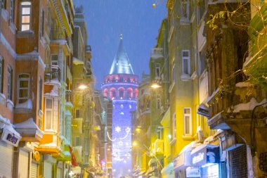  İstanbul 'da kış. Dar bir sokaktan tarihi Galata Kulesi manzarası ve karlı hava.