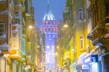  İstanbul 'da kış. Dar bir sokaktan tarihi Galata Kulesi manzarası ve karlı hava.