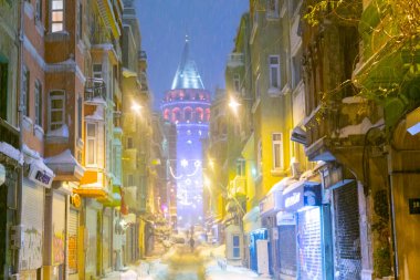  İstanbul 'da kış. Dar bir sokaktan tarihi Galata Kulesi manzarası ve karlı hava.