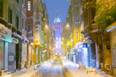  İstanbul 'da kış. Dar bir sokaktan tarihi Galata Kulesi manzarası ve karlı hava.