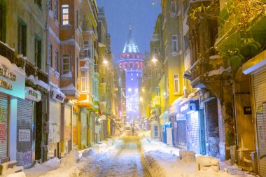  İstanbul 'da kış. Dar bir sokaktan tarihi Galata Kulesi manzarası ve karlı hava.