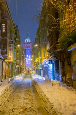  İstanbul 'da kış. Dar bir sokaktan tarihi Galata Kulesi manzarası ve karlı hava.