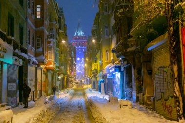  İstanbul 'da kış. Dar bir sokaktan tarihi Galata Kulesi manzarası ve karlı hava.