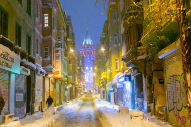  İstanbul 'da kış. Dar bir sokaktan tarihi Galata Kulesi manzarası ve karlı hava.