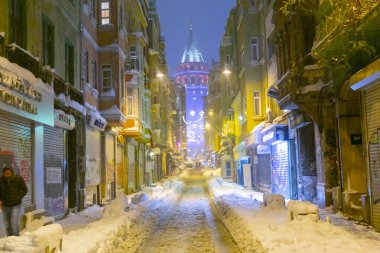  İstanbul 'da kış. Dar bir sokaktan tarihi Galata Kulesi manzarası ve karlı hava.