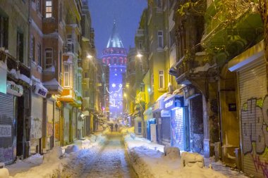  İstanbul 'da kış. Dar bir sokaktan tarihi Galata Kulesi manzarası ve karlı hava.