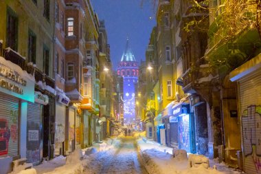  İstanbul 'da kış. Dar bir sokaktan tarihi Galata Kulesi manzarası ve karlı hava.