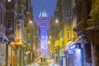  İstanbul 'da kış. Dar bir sokaktan tarihi Galata Kulesi manzarası ve karlı hava.