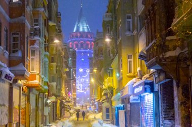  İstanbul 'da kış. Dar bir sokaktan tarihi Galata Kulesi manzarası ve karlı hava.