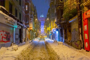  İstanbul 'da kış. Dar bir sokaktan tarihi Galata Kulesi manzarası ve karlı hava.