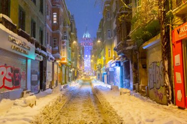  İstanbul 'da kış. Dar bir sokaktan tarihi Galata Kulesi manzarası ve karlı hava.