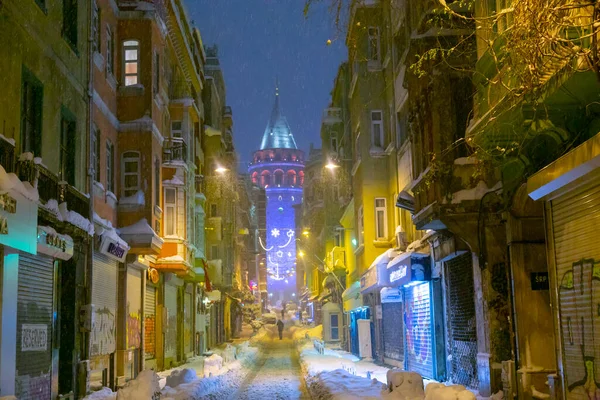  İstanbul 'da kış. Dar bir sokaktan tarihi Galata Kulesi manzarası ve karlı hava.