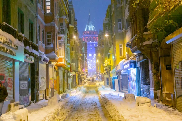  İstanbul 'da kış. Dar bir sokaktan tarihi Galata Kulesi manzarası ve karlı hava.