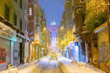  İstanbul 'da kış. Dar bir sokaktan tarihi Galata Kulesi manzarası ve karlı hava.