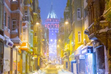  İstanbul 'da kış. Dar bir sokaktan tarihi Galata Kulesi manzarası ve karlı hava.