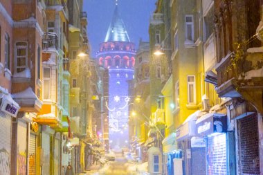  İstanbul 'da kış. Dar bir sokaktan tarihi Galata Kulesi manzarası ve karlı hava.
