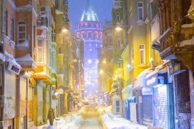  İstanbul 'da kış. Dar bir sokaktan tarihi Galata Kulesi manzarası ve karlı hava.