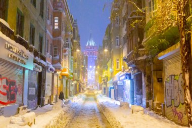  İstanbul 'da kış. Dar bir sokaktan tarihi Galata Kulesi manzarası ve karlı hava.
