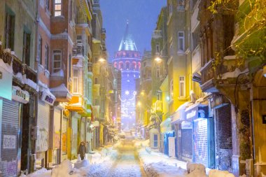  İstanbul 'da kış. Dar bir sokaktan tarihi Galata Kulesi manzarası ve karlı hava.