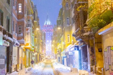  İstanbul 'da kış. Dar bir sokaktan tarihi Galata Kulesi manzarası ve karlı hava.