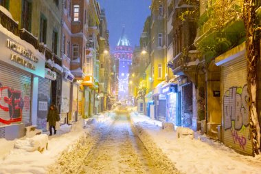  İstanbul 'da kış. Dar bir sokaktan tarihi Galata Kulesi manzarası ve karlı hava.