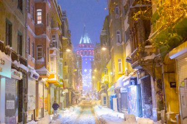  İstanbul 'da kış. Dar bir sokaktan tarihi Galata Kulesi manzarası ve karlı hava.