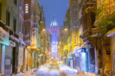  İstanbul 'da kış. Dar bir sokaktan tarihi Galata Kulesi manzarası ve karlı hava.