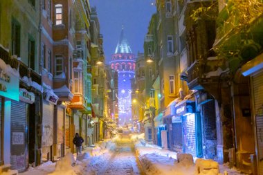  İstanbul 'da kış. Dar bir sokaktan tarihi Galata Kulesi manzarası ve karlı hava.
