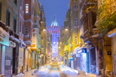  İstanbul 'da kış. Dar bir sokaktan tarihi Galata Kulesi manzarası ve karlı hava.