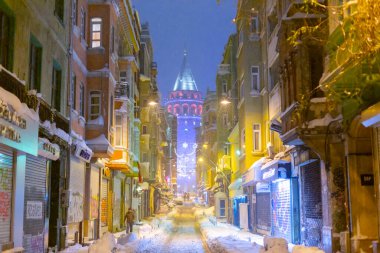  İstanbul 'da kış. Dar bir sokaktan tarihi Galata Kulesi manzarası ve karlı hava.