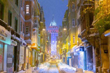  İstanbul 'da kış. Dar bir sokaktan tarihi Galata Kulesi manzarası ve karlı hava.