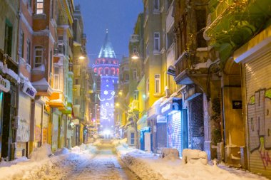  İstanbul 'da kış. Dar bir sokaktan tarihi Galata Kulesi manzarası ve karlı hava.