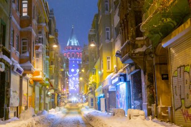  İstanbul 'da kış. Dar bir sokaktan tarihi Galata Kulesi manzarası ve karlı hava.