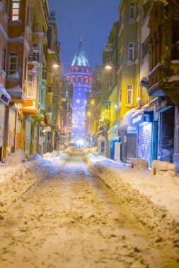  İstanbul 'da kış. Dar bir sokaktan tarihi Galata Kulesi manzarası ve karlı hava.