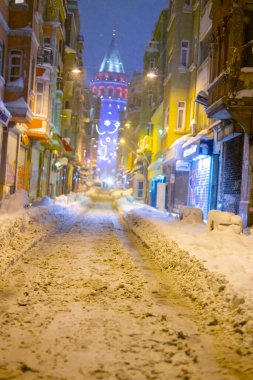  İstanbul 'da kış. Dar bir sokaktan tarihi Galata Kulesi manzarası ve karlı hava.
