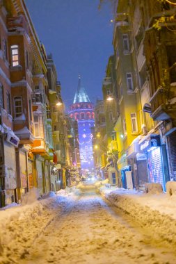  İstanbul 'da kış. Dar bir sokaktan tarihi Galata Kulesi manzarası ve karlı hava.