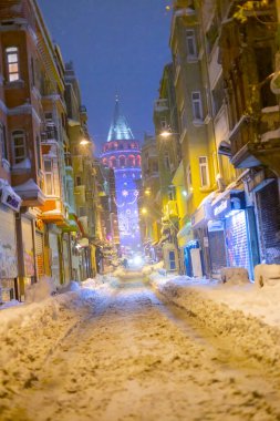  İstanbul 'da kış. Dar bir sokaktan tarihi Galata Kulesi manzarası ve karlı hava.