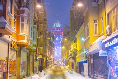 İstanbul 'da kış. Dar bir sokaktan tarihi Galata Kulesi manzarası ve karlı hava.
