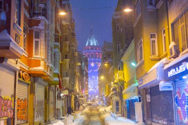  İstanbul 'da kış. Dar bir sokaktan tarihi Galata Kulesi manzarası ve karlı hava.