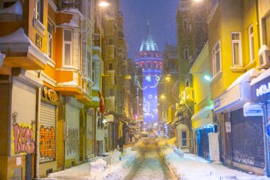  İstanbul 'da kış. Dar bir sokaktan tarihi Galata Kulesi manzarası ve karlı hava.
