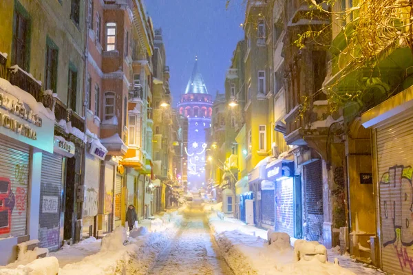  İstanbul 'da kış. Dar bir sokaktan tarihi Galata Kulesi manzarası ve karlı hava.
