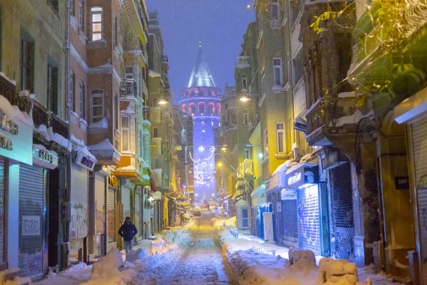  İstanbul 'da kış. Dar bir sokaktan tarihi Galata Kulesi manzarası ve karlı hava.