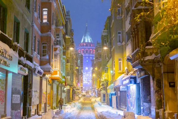  İstanbul 'da kış. Dar bir sokaktan tarihi Galata Kulesi manzarası ve karlı hava.