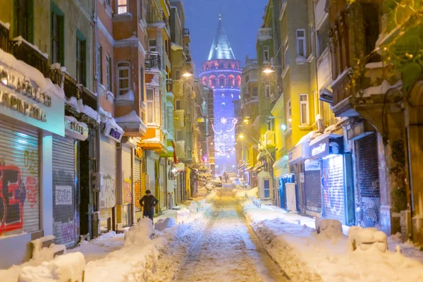  İstanbul 'da kış. Dar bir sokaktan tarihi Galata Kulesi manzarası ve karlı hava.